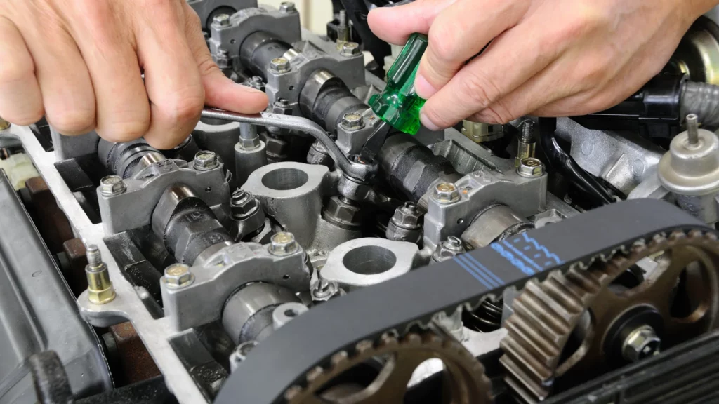 Zdjęcie prezentuje dokręcanie głowicy samochodowej za pomocą klucza przez mechanika