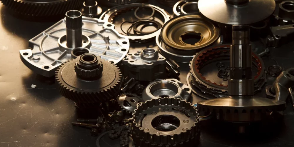 Zdjęcie przedstawia części samochodowe, na tle stołu warsztatowego.